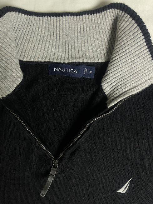 Close-up of vintage Nautica black quarter-zip sweater collar showing grey ribbed lining, size XL tag, silver zipper pull, and embroidered sail chest logo