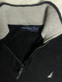 Close-up of vintage Nautica black quarter-zip sweater collar showing grey ribbed lining, size XL tag, silver zipper pull, and embroidered sail chest logo