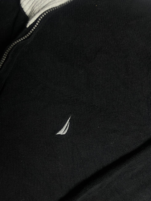 Close-up of vintage Nautica black quarter-zip sweater collar showing grey ribbed lining, size XL tag, silver zipper pull, and embroidered sail chest logo