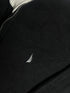 Close-up of vintage Nautica black quarter-zip sweater collar showing grey ribbed lining, size XL tag, silver zipper pull, and embroidered sail chest logo