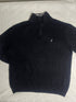 Close-up of vintage Nautica black quarter-zip sweater collar showing grey ribbed lining, size XL tag, silver zipper pull, and embroidered sail chest logo