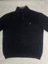 Close-up of vintage Nautica black quarter-zip sweater collar showing grey ribbed lining, size XL tag, silver zipper pull, and embroidered sail chest logo